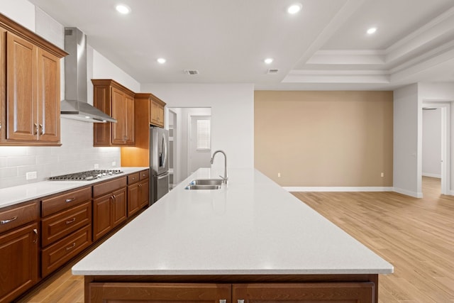 kitchen featuring light hardwood / wood-style floors, stainless steel appliances, sink, a large island, and wall chimney range hood