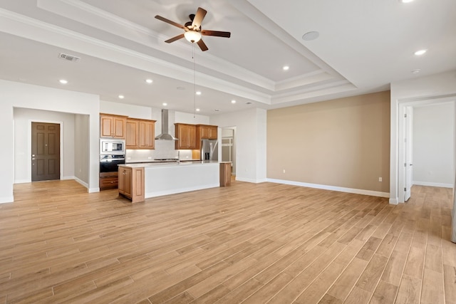 unfurnished living room featuring light wood-type flooring, a tray ceiling, ceiling fan, and crown molding