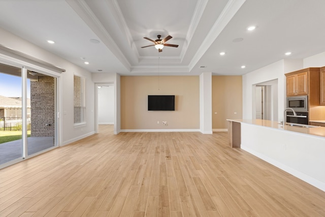 unfurnished living room with light hardwood / wood-style floors, ceiling fan, crown molding, and sink