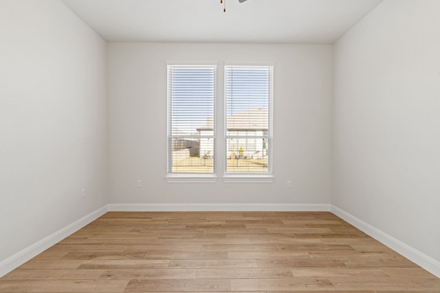 empty room featuring a wealth of natural light, ceiling fan, and light hardwood / wood-style flooring