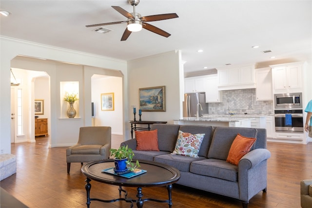 living room with ceiling fan, sink, dark hardwood / wood-style floors, and crown molding