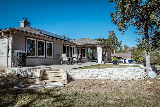 back of property with solar panels and a patio area