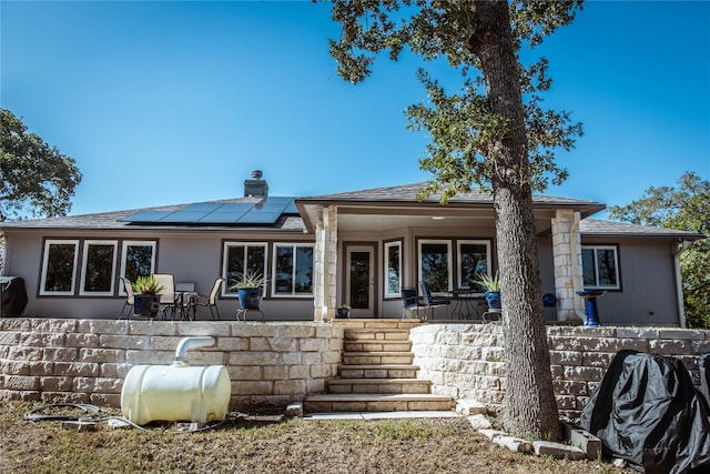 back of property featuring solar panels and covered porch