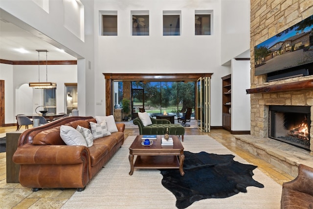 living room with a high ceiling, a chandelier, built in shelves, and a fireplace