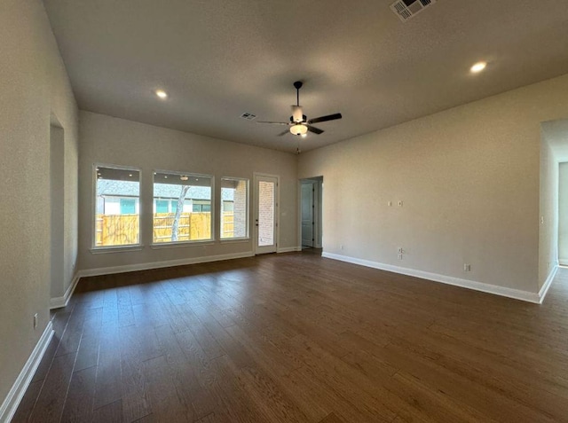 unfurnished room featuring visible vents, baseboards, dark wood-style floors, and a ceiling fan