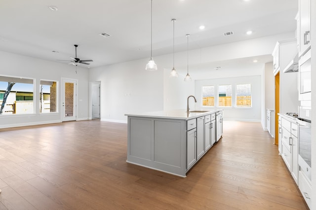 kitchen featuring visible vents, light wood-type flooring, ceiling fan, and a sink