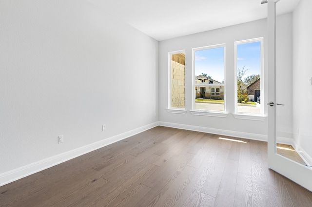 unfurnished room with baseboards and dark wood-type flooring