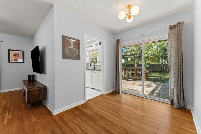 7909 Tisdale Dr, Austin, TX 78757 - doorway with light wood-style floors, a sink, a chandelier, and baseboards