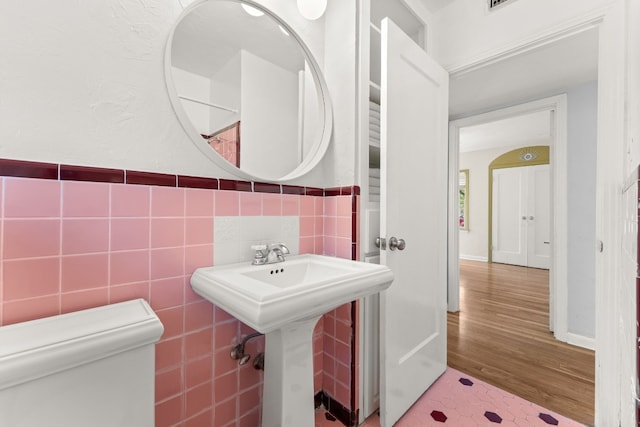 7909 Tisdale Dr, Austin, TX 78757 - half bathroom with toilet, wood finished floors, a sink, and tile walls