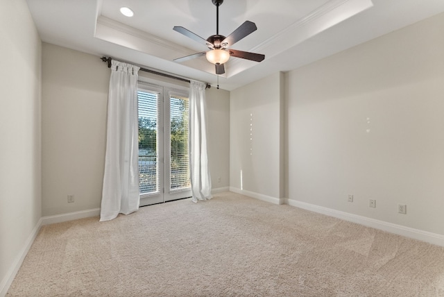 unfurnished room featuring a tray ceiling, light carpet, crown molding, and ceiling fan