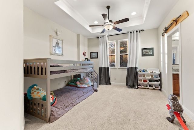 bedroom with carpet flooring, ceiling fan, ornamental molding, and a tray ceiling