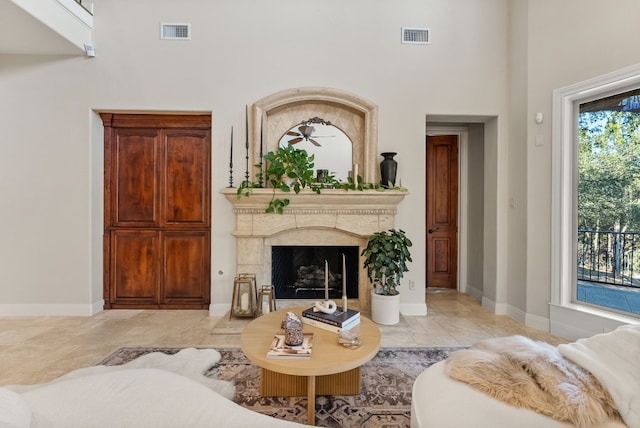 living room featuring ceiling fan, a wealth of natural light, and a premium fireplace