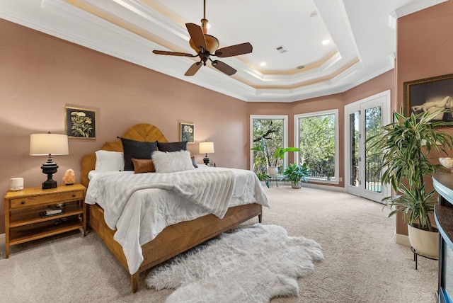 carpeted bedroom with ceiling fan, access to exterior, ornamental molding, and a tray ceiling