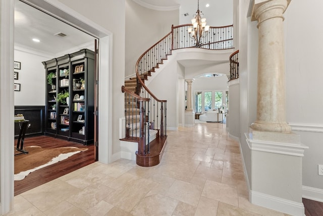 foyer entrance with decorative columns, crown molding, french doors, and a chandelier