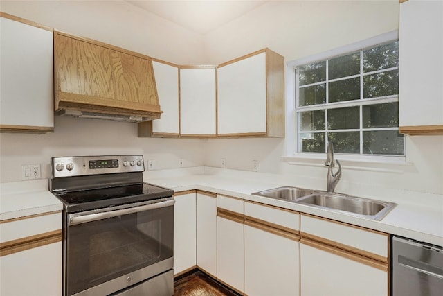 kitchen featuring appliances with stainless steel finishes, premium range hood, white cabinetry, and sink