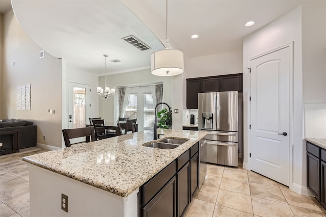 kitchen featuring light stone counters, a center island with sink, appliances with stainless steel finishes, pendant lighting, and sink