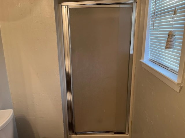 bathroom featuring a shower with shower door and toilet