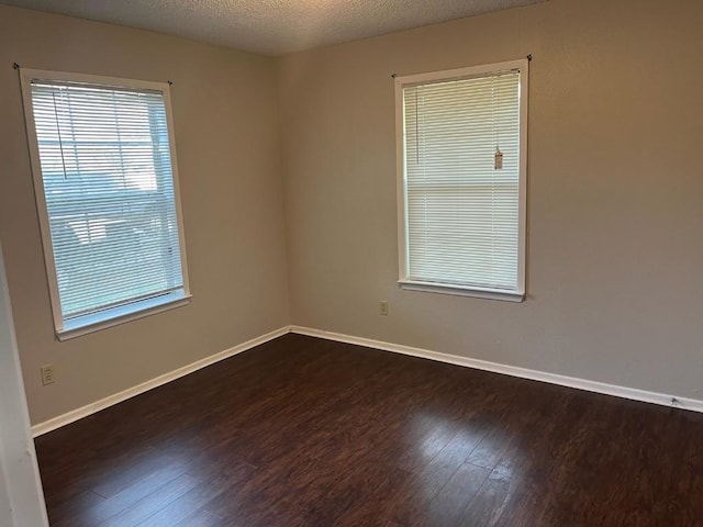 empty room featuring dark hardwood / wood-style floors and a textured ceiling