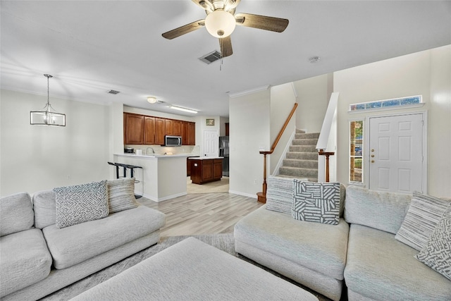 living room featuring ceiling fan with notable chandelier and light hardwood / wood-style flooring