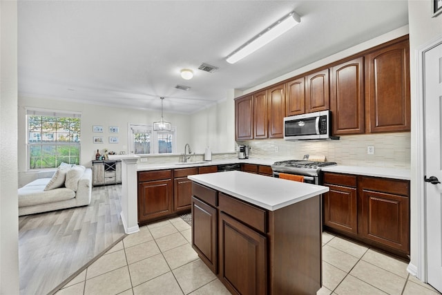 kitchen with appliances with stainless steel finishes, light tile patterned floors, pendant lighting, sink, and kitchen peninsula