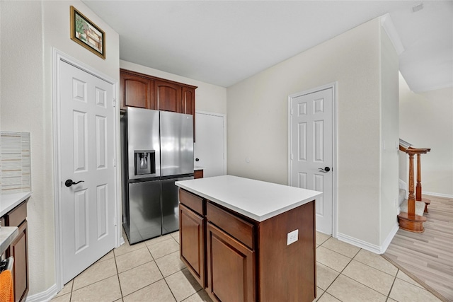 kitchen featuring stainless steel fridge with ice dispenser, light tile patterned floors, and a kitchen island