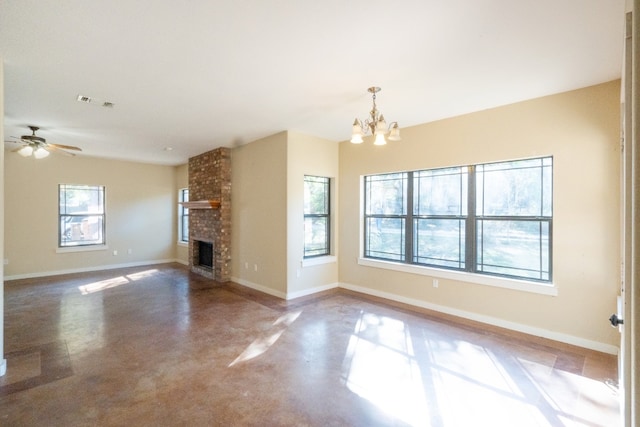 unfurnished living room with a brick fireplace, ceiling fan with notable chandelier, and concrete floors