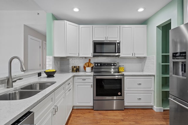 kitchen featuring white cabinets, light wood-type flooring, appliances with stainless steel finishes, and sink