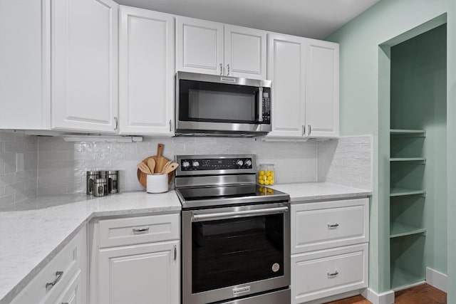 kitchen with stainless steel appliances, light stone countertops, and white cabinets