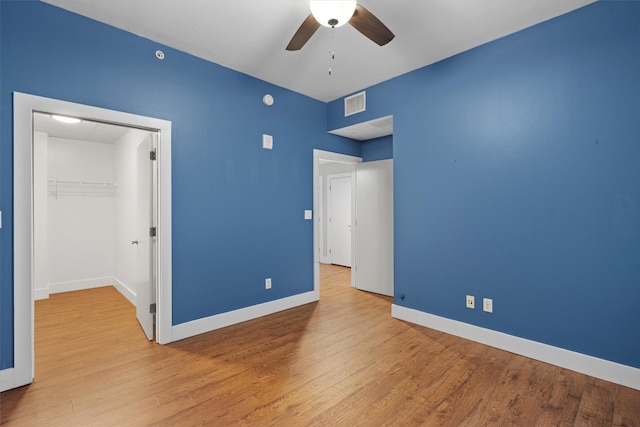 unfurnished bedroom with ceiling fan, a closet, light hardwood / wood-style flooring, and a spacious closet