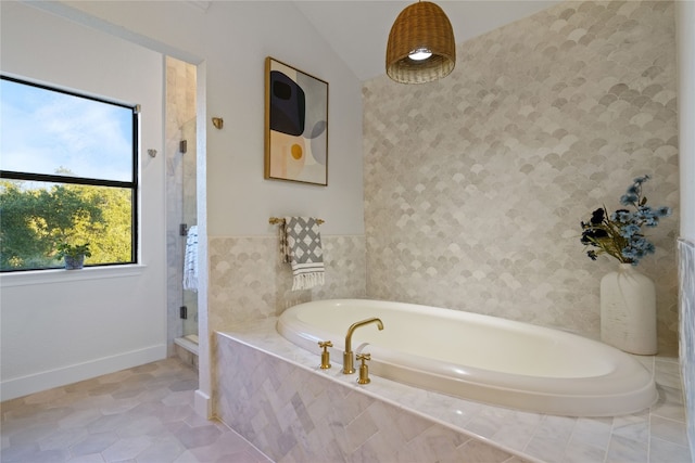 bathroom featuring tile patterned floors, tile walls, vaulted ceiling, and shower with separate bathtub