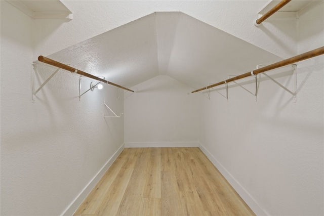 spacious closet with hardwood / wood-style floors and vaulted ceiling