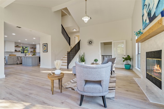 living room with a tile fireplace, light hardwood / wood-style flooring, high vaulted ceiling, and a wealth of natural light