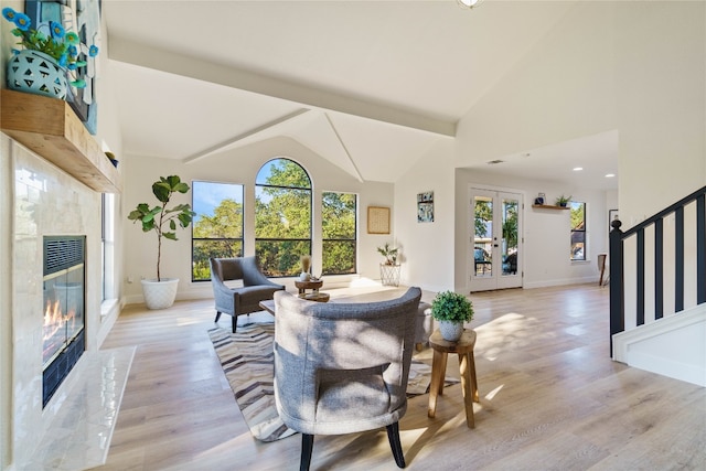 living room with french doors, light wood-type flooring, high vaulted ceiling, and a wealth of natural light