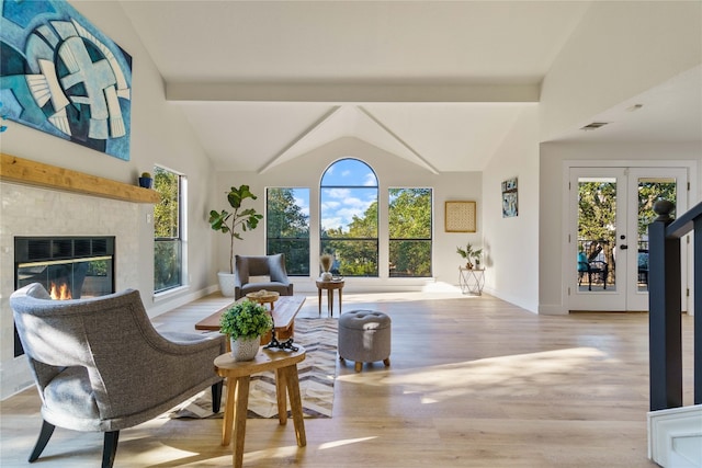 living room featuring french doors, beamed ceiling, light hardwood / wood-style floors, and high vaulted ceiling