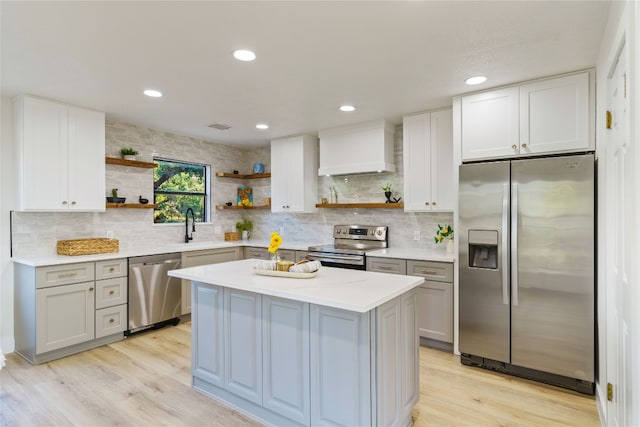 kitchen with appliances with stainless steel finishes, tasteful backsplash, custom range hood, light hardwood / wood-style flooring, and a kitchen island