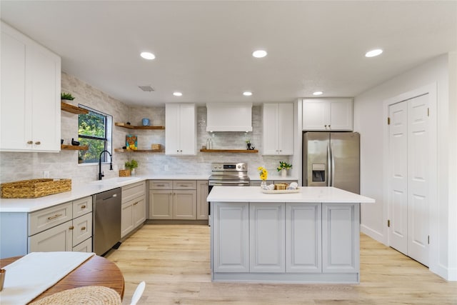 kitchen with appliances with stainless steel finishes, light wood-type flooring, custom range hood, and sink