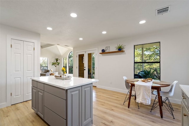 kitchen featuring light hardwood / wood-style flooring, vaulted ceiling, a center island, and gray cabinets