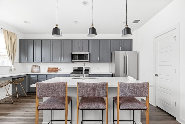 kitchen with dark wood-style floors, light countertops, stainless steel appliances, gray cabinetry, and a sink