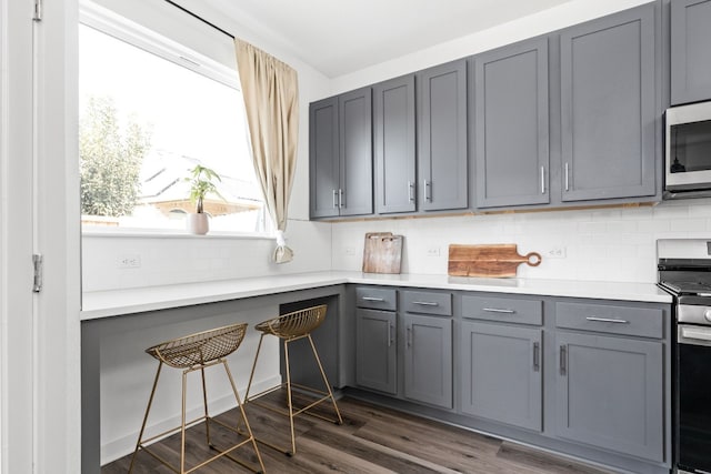 kitchen featuring dark wood-style floors, appliances with stainless steel finishes, light countertops, gray cabinetry, and backsplash