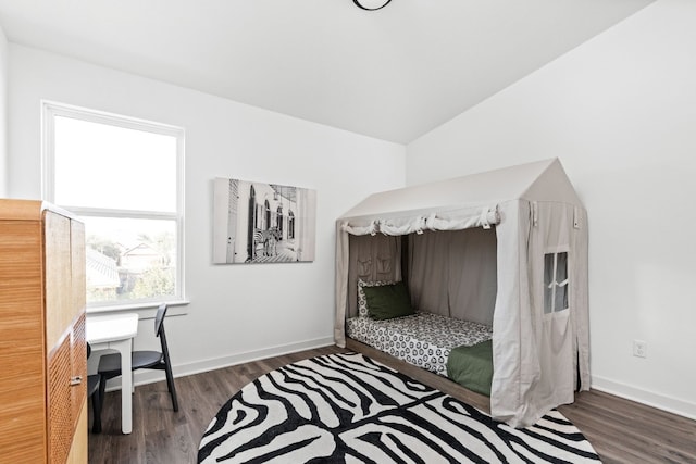 bedroom with baseboards, vaulted ceiling, and wood finished floors