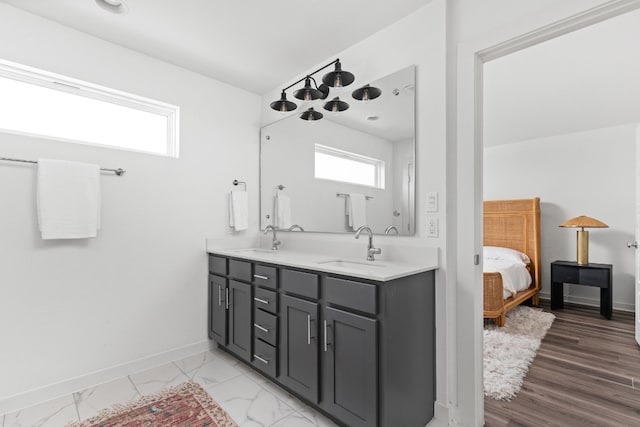 ensuite bathroom with marble finish floor, a sink, and baseboards