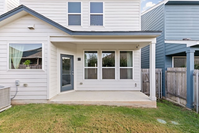 rear view of house with central AC unit, a lawn, a patio area, and fence