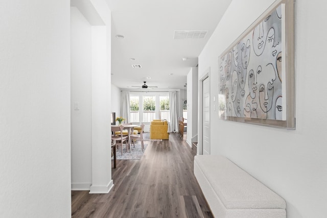 hallway featuring wood finished floors, visible vents, and baseboards