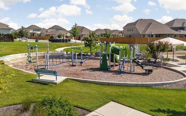 community play area featuring a yard, fence, and a residential view