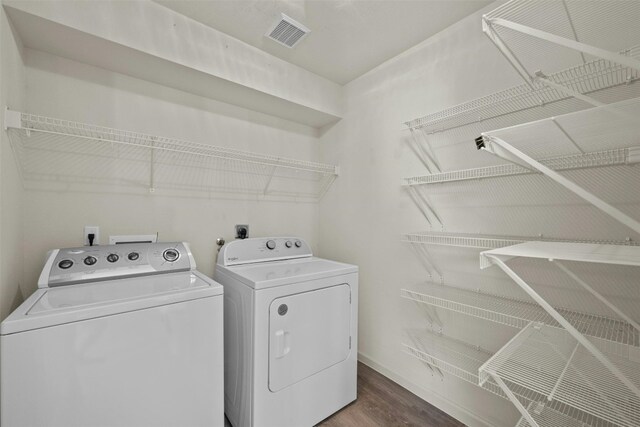 clothes washing area with wood-type flooring and washer and dryer