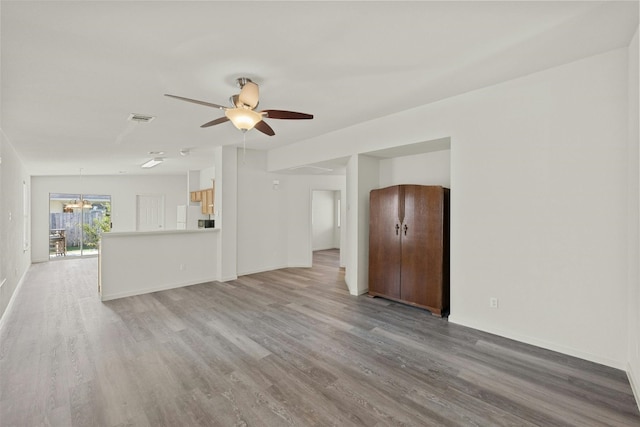 unfurnished living room with ceiling fan with notable chandelier and light hardwood / wood-style floors