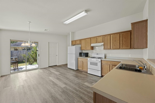 kitchen featuring white appliances, light hardwood / wood-style floors, sink, and hanging light fixtures