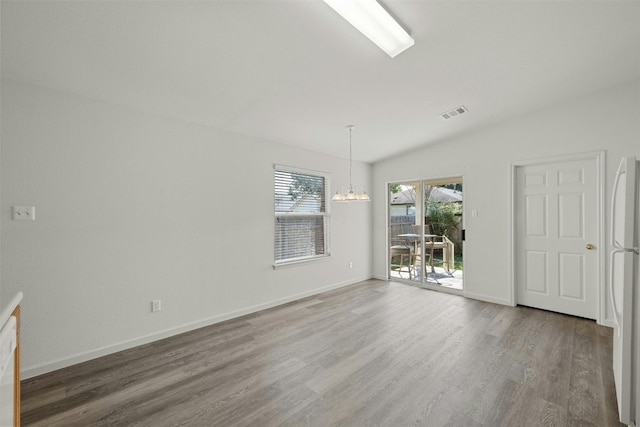 empty room with hardwood / wood-style floors and a notable chandelier