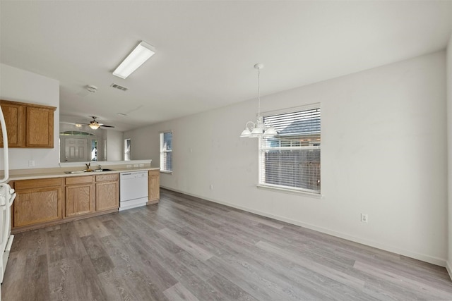 kitchen featuring sink, light hardwood / wood-style flooring, hanging light fixtures, white dishwasher, and ceiling fan with notable chandelier