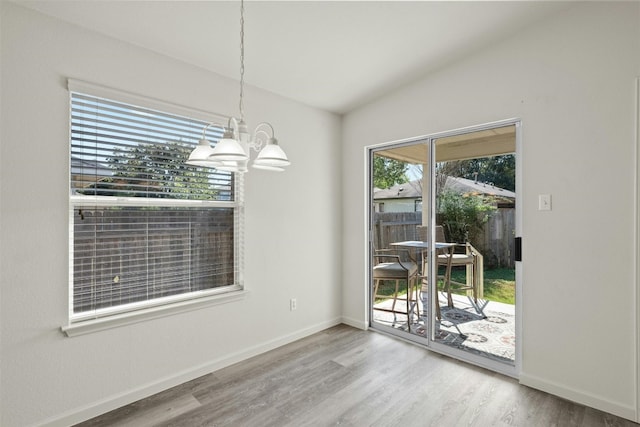 unfurnished dining area with an inviting chandelier, lofted ceiling, and wood-type flooring